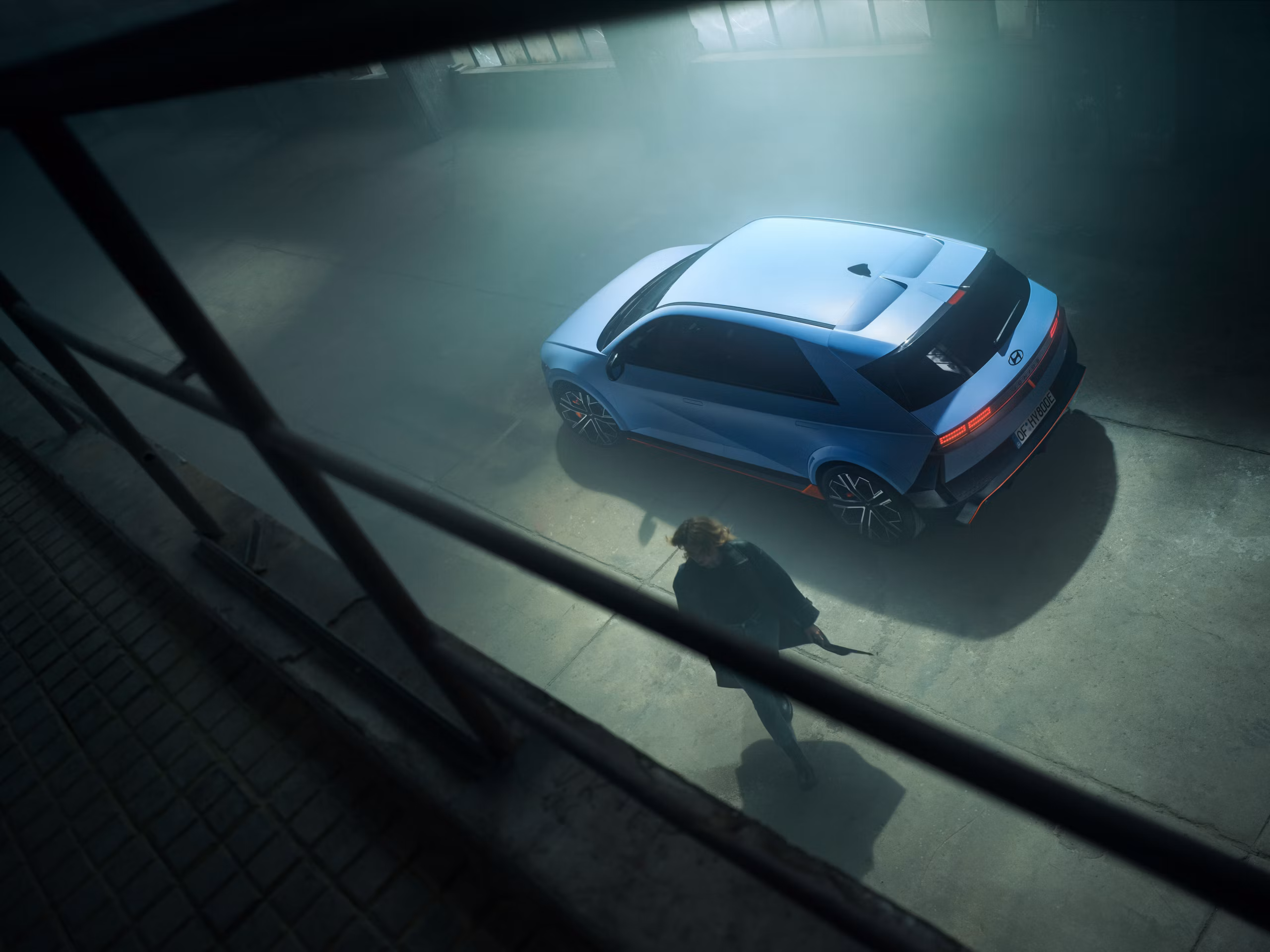 A person walks next to the all-electric Hyundai IONIQ 5 N parked inside a building. 